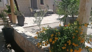 Un patio con pared de piedra, plantas en macetas y una mesa con sillas.