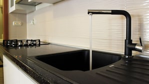 Una cocina con encimera negra, un lavabo y un grifo.