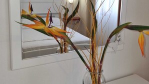 A bathroom with a mirror, a vase with dried plants, and a wall-mounted light fixture. - Apartments Hani (Postira)
