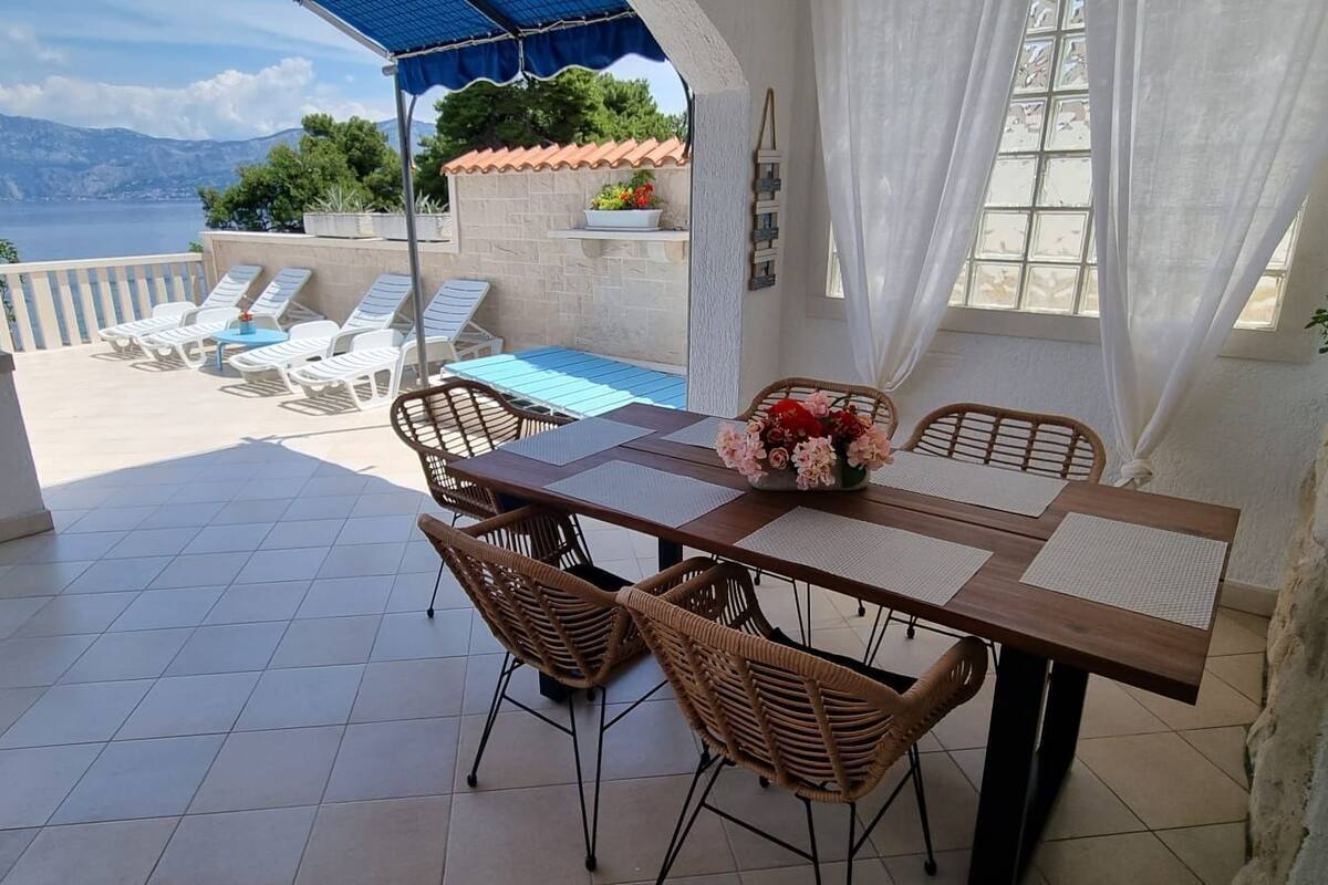 A terrace with a table and chairs, a view of the sea, and a pool.