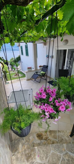 Un patio con plantas colgantes, zona de estar y vista al mar.