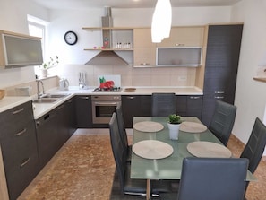 Cocina compacta con comedor, que incluye estufa, fregadero y armarios.