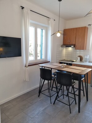 Una cocina moderna con zona de comedor, que incluye un televisor de pantalla plana, armarios de madera y salpicadero de azulejos.
