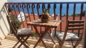 A balcony with a table and chairs, a bowl of fruit, and a view of the sea. - Apartment Sunny Apartment (Bol)
