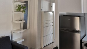 A modern kitchen with a built-in refrigerator, a ceiling fan, and a white shelving unit with a plant. - Apartments Natasa (Supetar)