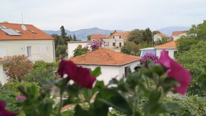A residential area with houses, a mountain in the background, and a balcony with pink flowers. - Apartments Natasa (Supetar)