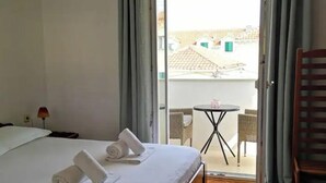 A hotel room with a bed, a small table, and a chair. - Apartments Natasa (Supetar)