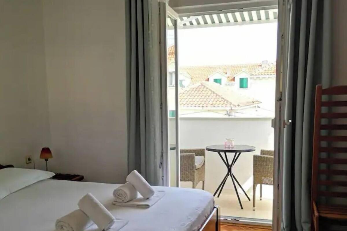 A hotel room with a bed, a small table, and a chair.