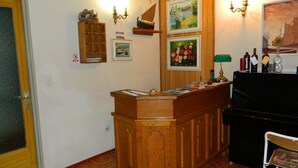 A wooden reception desk with a counter, a small shelf with decorative items, and framed pictures on the wall. - Apartment and Room Darinka (Vrboska)