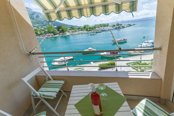 A balcony with a table, chairs, and a bottle of wine.