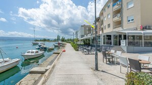 Hotel frente al mar con terraza al aire libre, un muelle con barcos y una vista despejada del océano.