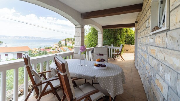 Un balcon avec une table dressée pour deux personnes, offrant une vue panoramique.