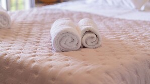 Un lit recouvert d’une courtepointe matelassée, avec deux serviettes blanches roulées posées dessus.