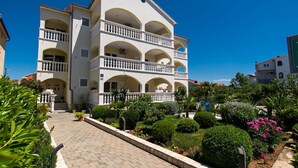 Um hotel com vários andares, um pátio central, varandas e um caminho pavimentado.
