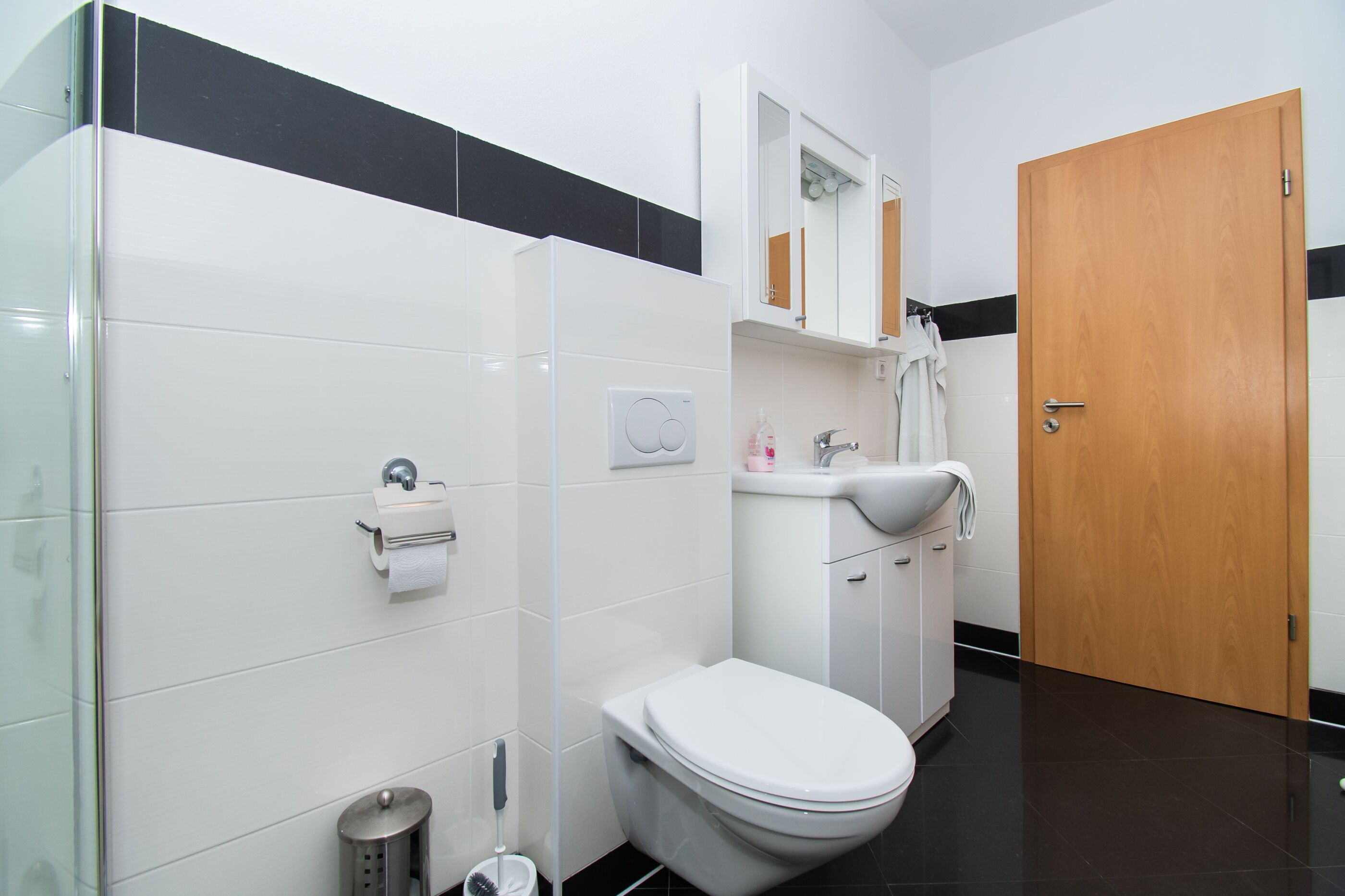 Un baño moderno con inodoro, lavamanos y espejo.