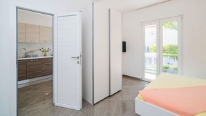 A bedroom with a bed, a sliding door to a bathroom, and a view of a balcony. - Apartment and Rooms Mato (Mlini)