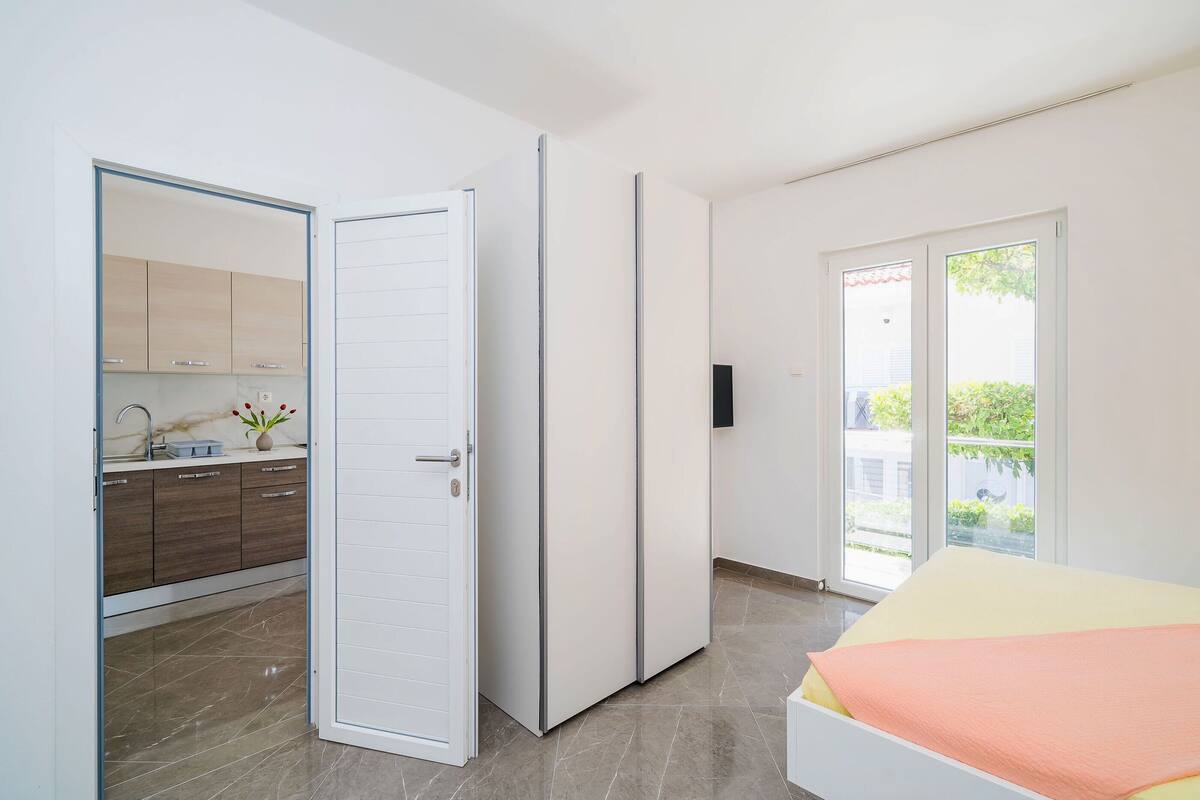 A bedroom with a bed, a sliding door to a bathroom, and a view of a balcony.