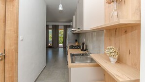 A modern kitchen with wooden cabinets, a stainless steel sink, and a hanging pendant light. - Apartments Koras (Kneza)
