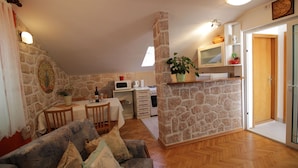 Un salón acogedor con pared de piedra, muebles de madera y una zona de cocina con microondas y estufa.