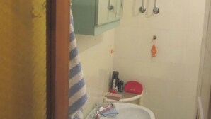 Ein Badezimmer mit Toilette, Waschbecken und Durchlauferhitzer.