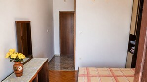 Ein Schlafzimmer mit einem Bett, einem Schminktisch, einem Spiegel und einer Vase mit Blumen.