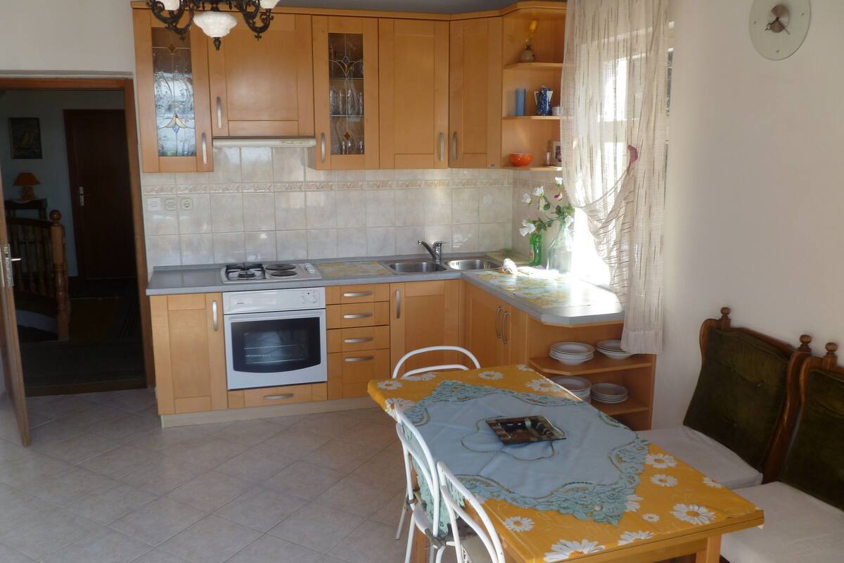 Une cuisine compacte avec des meubles en bois, un four encastré et un coin repas comprenant une table et des chaises.