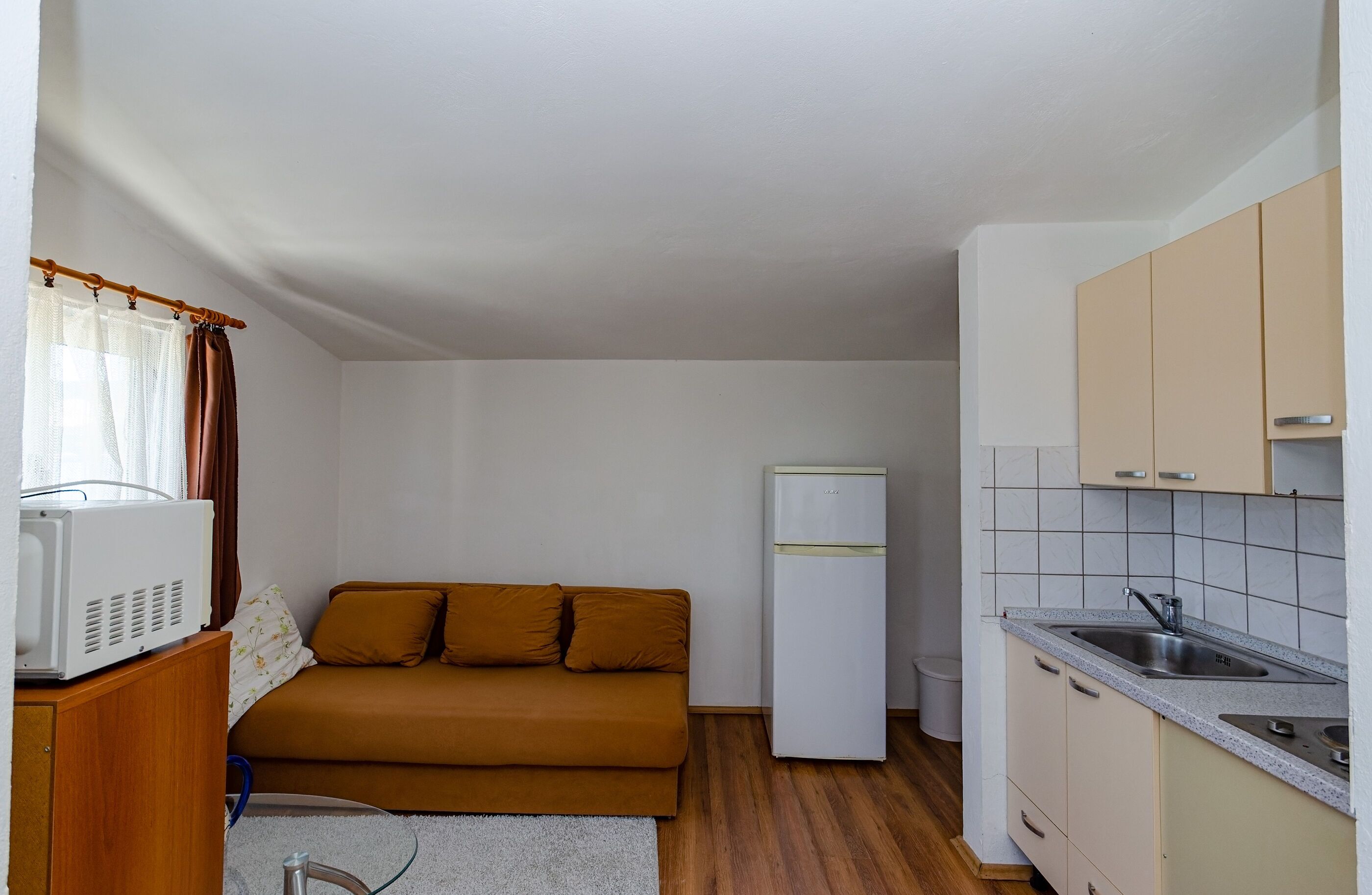 A compact kitchen with a refrigerator, a sink, and wooden cabinets.