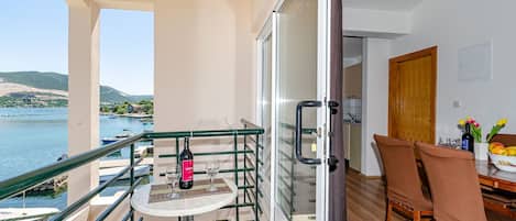 A balcony with a table, chairs, and a bottle of wine.
