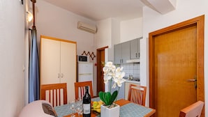 A dining area with a table set for two, a bottle of wine, and a potted orchid. - Apartments Oliver (Putnikovic)