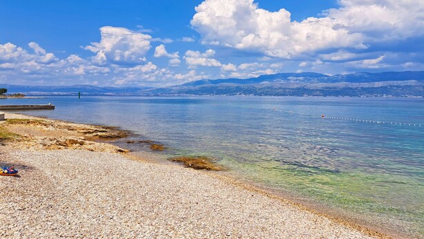 A pebbled beach with clear water and distant mountains. - Apartment Lada (Supetar)