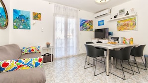A modern living room with a sofa, colorful cushions, a dining table with chairs, and artwork on the walls. - Apartment Lada (Supetar)