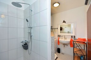 A modern bathroom with a shower, sink, and mirror. - Apartment Pepica (Postira)