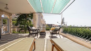 A balcony with a checkered floor, two lounge chairs, a small table, and a striped canopy. - Apartment Pepica (Postira)