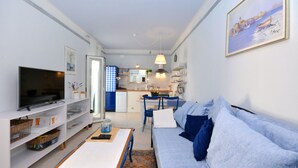 A compact living space with a sofa, TV, kitchen area, and dining table. - Apartment Pepica (Postira)