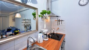 A modern kitchen with a large mirror, a coffee maker, and hanging plants. - Apartment Pepica (Postira)