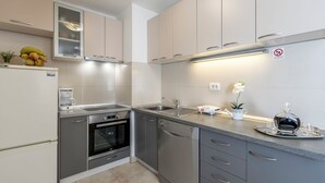 Una cocina moderna con armarios grises, horno empotrado, lavavajillas y pileta de acero inoxidable.