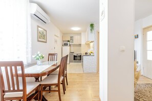 A modern kitchen with white cabinets, a microwave, and a small island with a sink. - Apartment Cvita (Split)