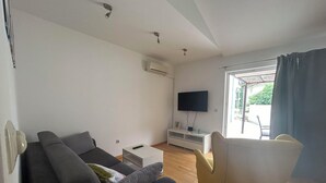 A modern living room with a grey sofa, a yellow armchair, a white TV stand, and a large window with curtains. - Apartment Ivana (Omis)