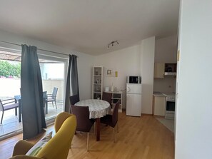 A compact living space with a dining area, kitchenette, and a view through a large window. - Apartment Ivana (Omis)