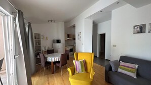 A living room with a yellow armchair, a gray sofa, and a dining area with a table and chairs. - Apartment Ivana (Omis)
