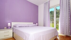 Une chambre à coucher avec un lit, une table de chevet et une fenêtre avec des rideaux.