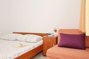 A bedroom with a bed, a nightstand, a dresser, and a sofa.
