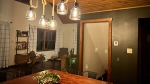 Un coin repas avec une table en bois, des chaises et un lustre dont les ampoules sont apparentes.