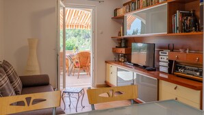 Un espace de vie compact comprenant un coin cuisine, un coin repas et une vue sur l’extérieur.