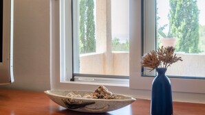 Une pièce avec une table en bois, un bol en céramique et un vase bleu contenant des fleurs séchées.
