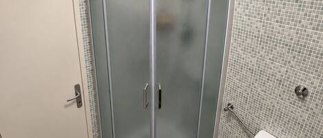 A bathroom with a glass-enclosed shower, a toilet, and a bathtub.