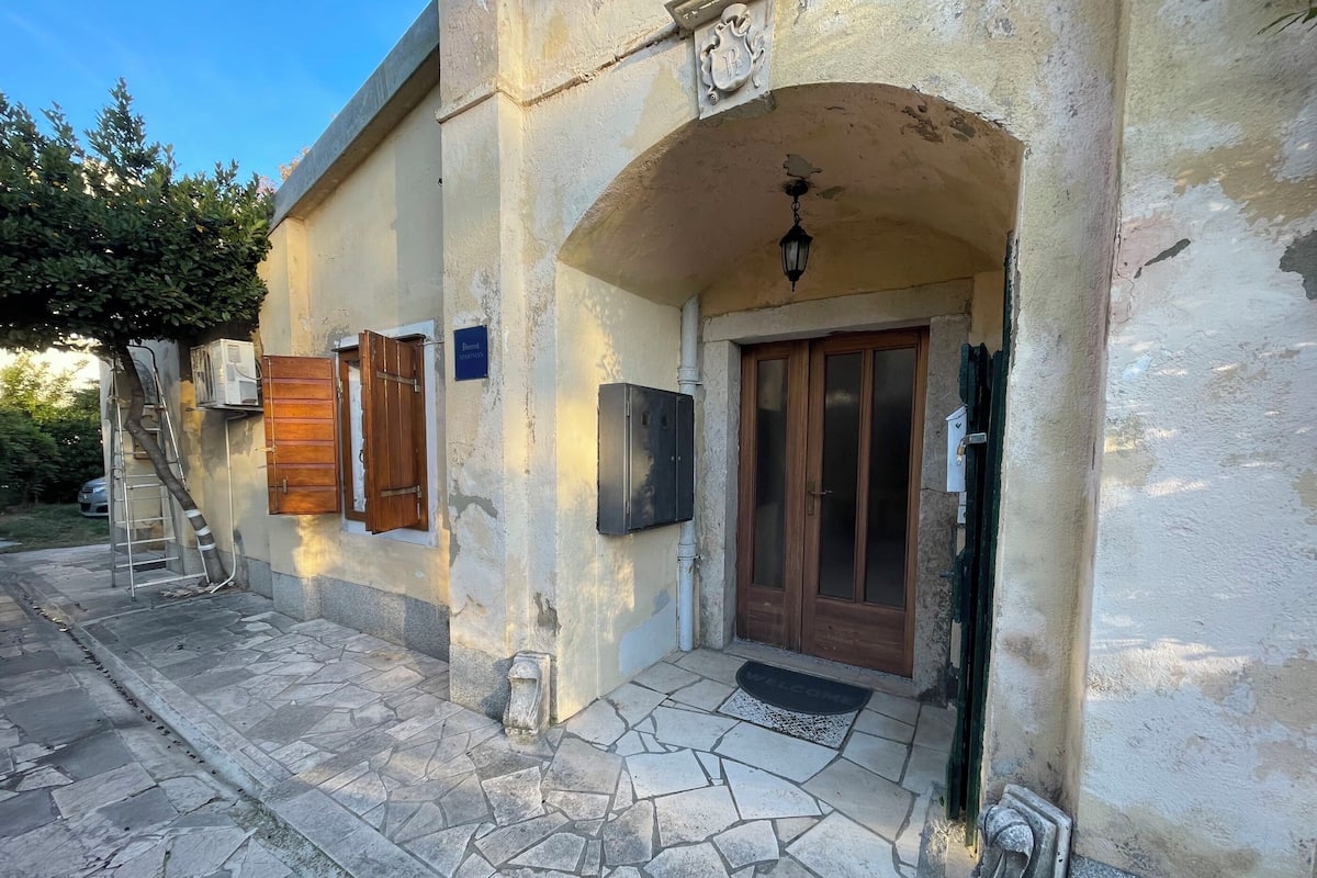 A building with a stone-paved entrance, a wooden door, and a welcome mat.