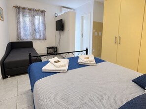 A bedroom with a bed, a sofa, a TV, and a wardrobe. - Apartments Jugo i Bura (Omis)