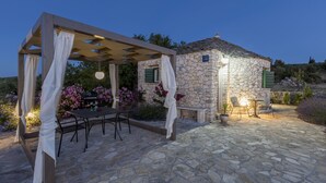 En byggnad i sten med en pergola och ett utomhusområde med sittplatser.