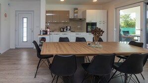 A modern kitchen with white cabinets, a wooden dining table, and black chairs. - House Villa Ivona (Suhovare)